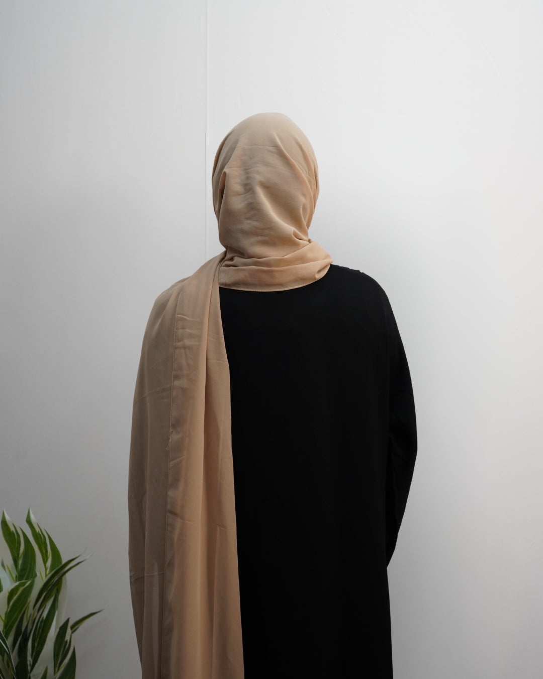 Woman wearing beige indian chiffon hijab from the back view.