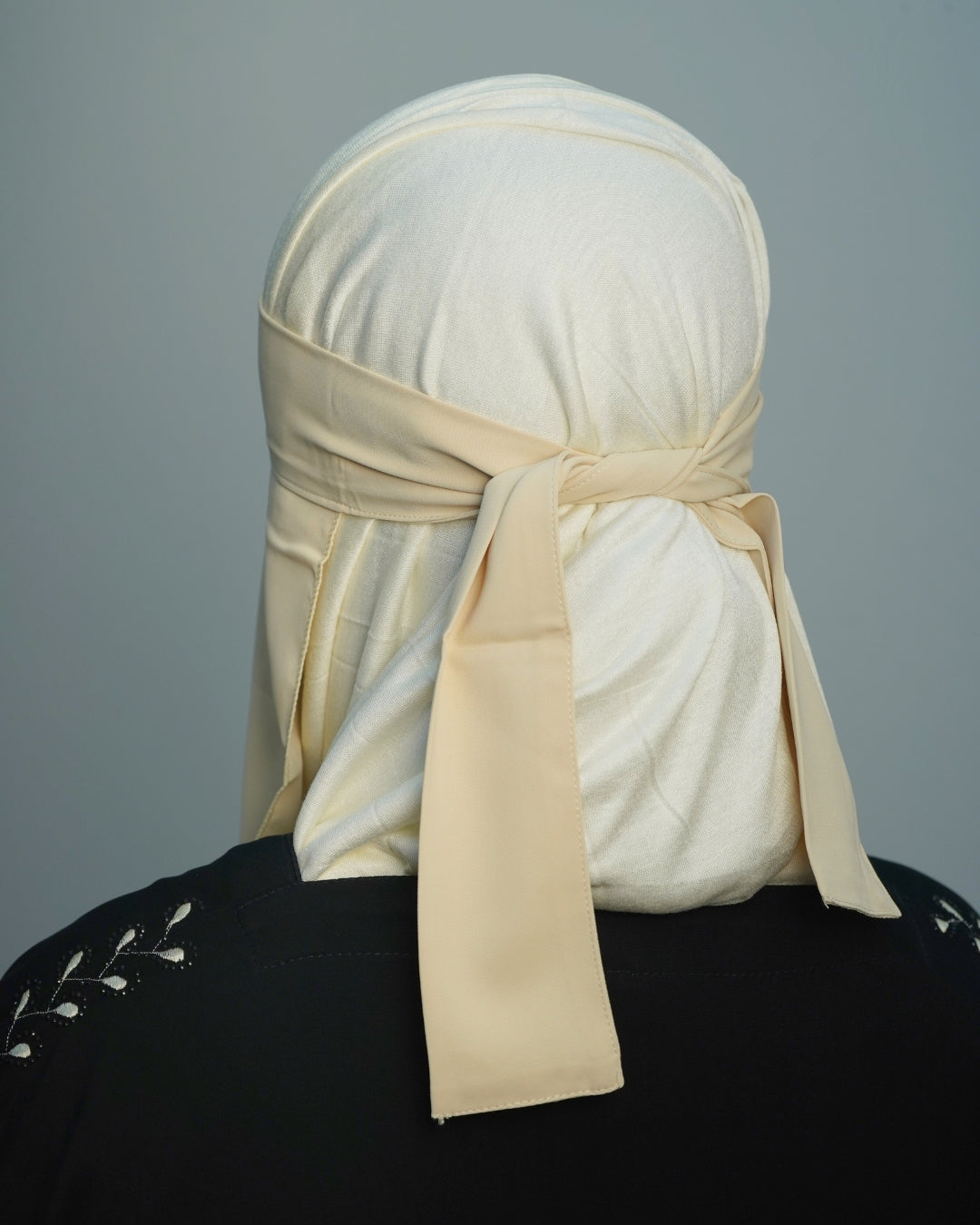 Back view of beige niqab with adjustable straps tied securely.