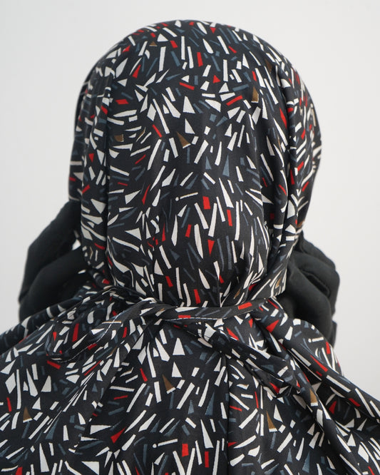 Close-up of black prayer dress back tie with abstract red, white, and grey print.