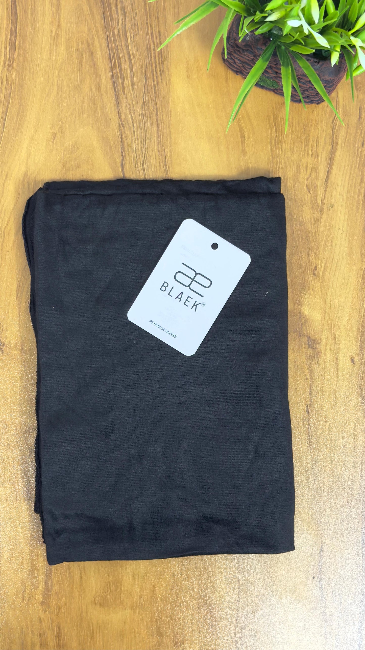 Classic black jersey hijab, folded with a smooth finish.