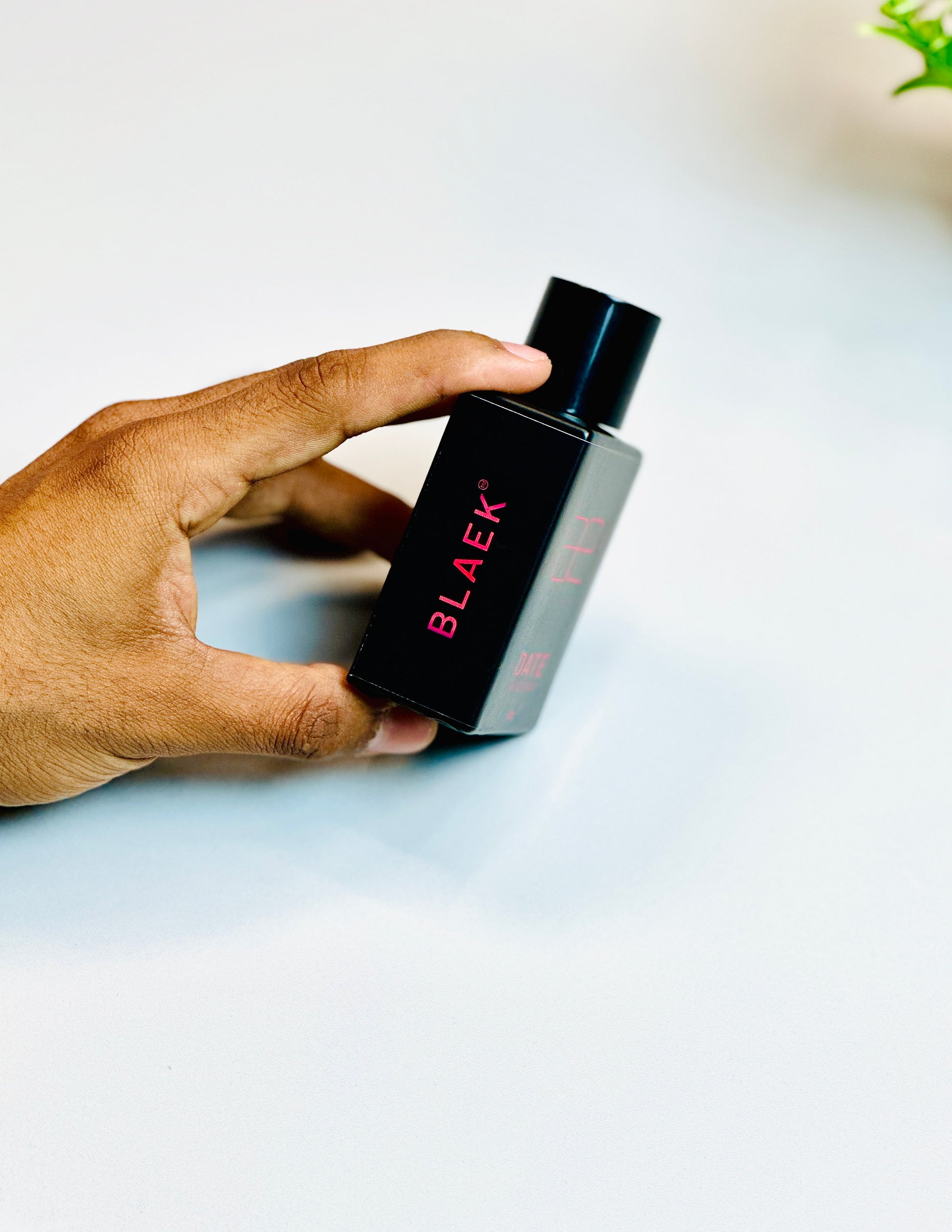 Blaek Date Perfume (50ml) bottle gripped gently for a detailed side view.