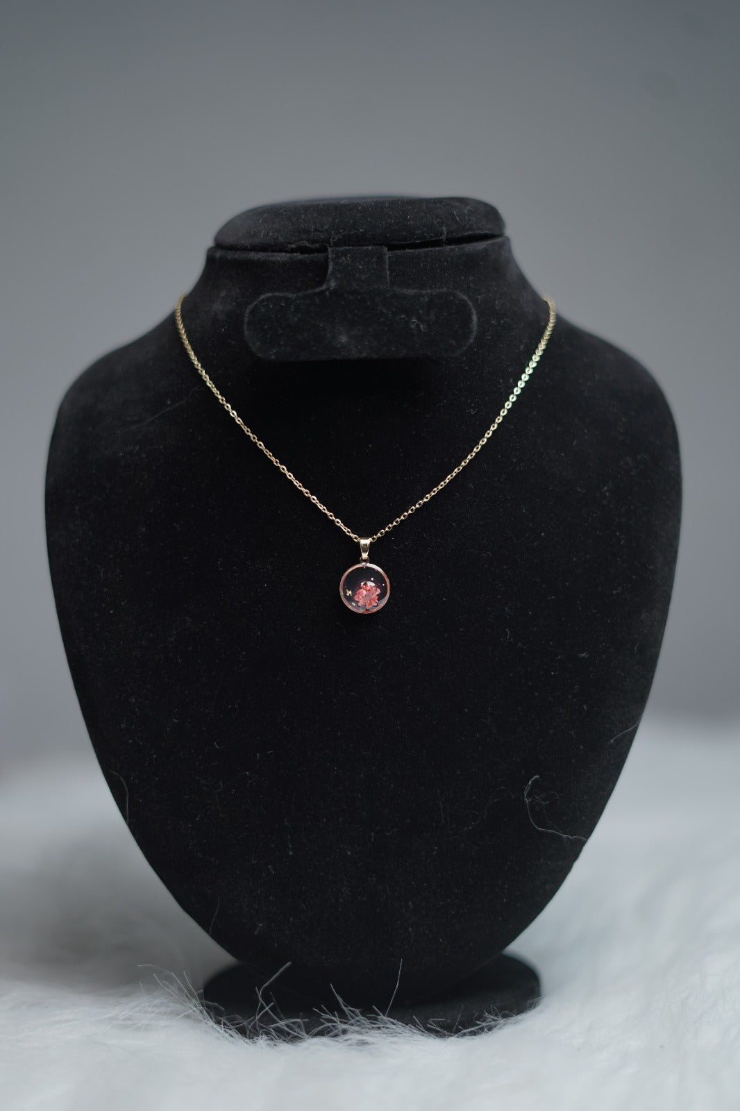 Blush Bloom Necklace hanging on display stand with pink floral pendant.