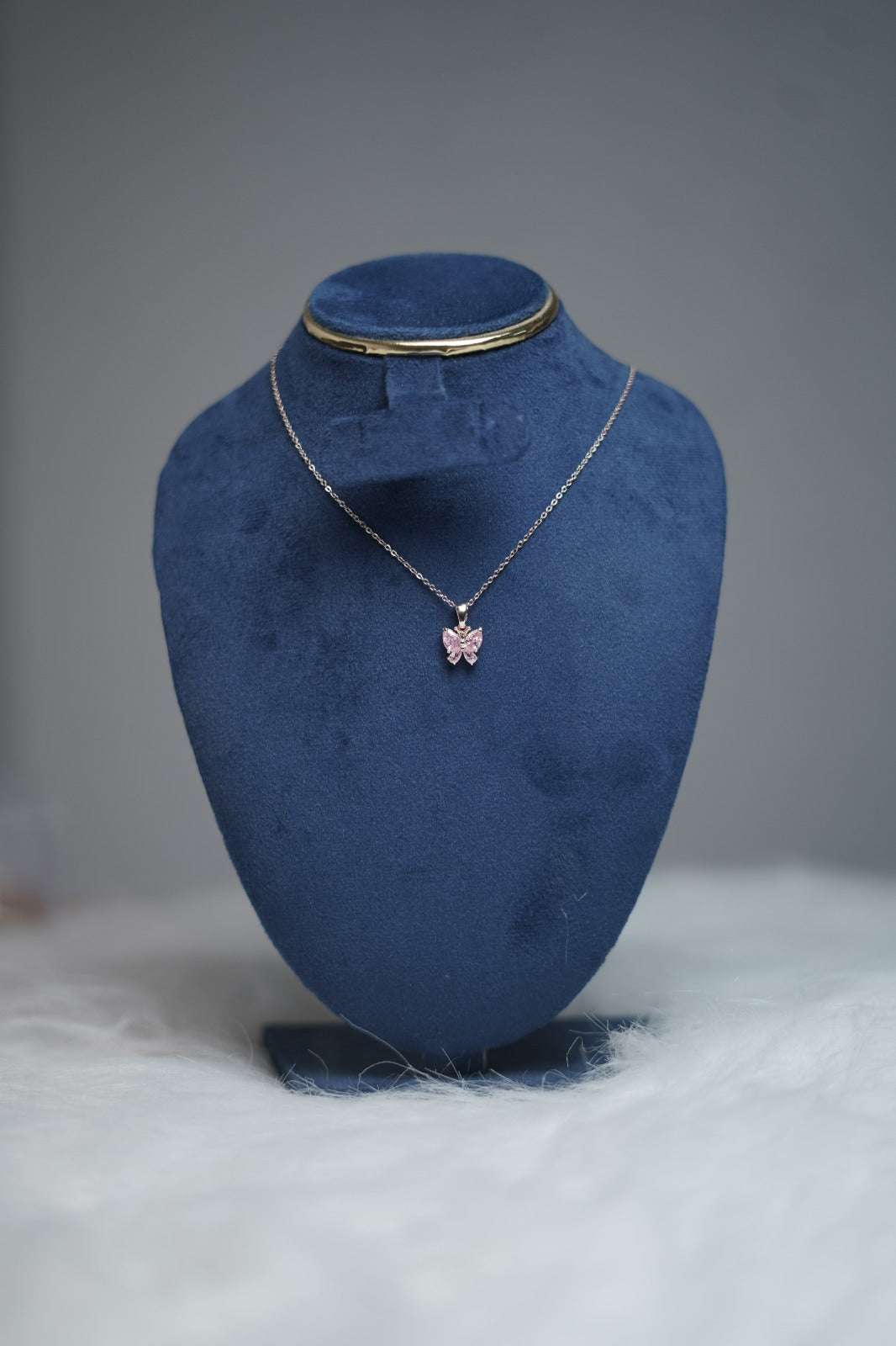 Pink butterfly pendant necklace displayed on a jewelry stand.