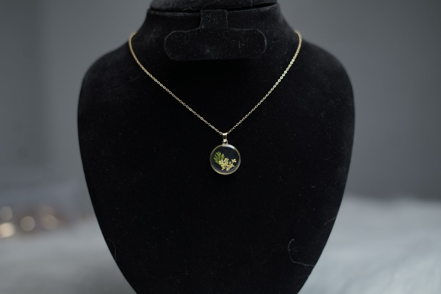 Botanical Bloom Necklace with dried flower pendant displayed on jewelry stand.