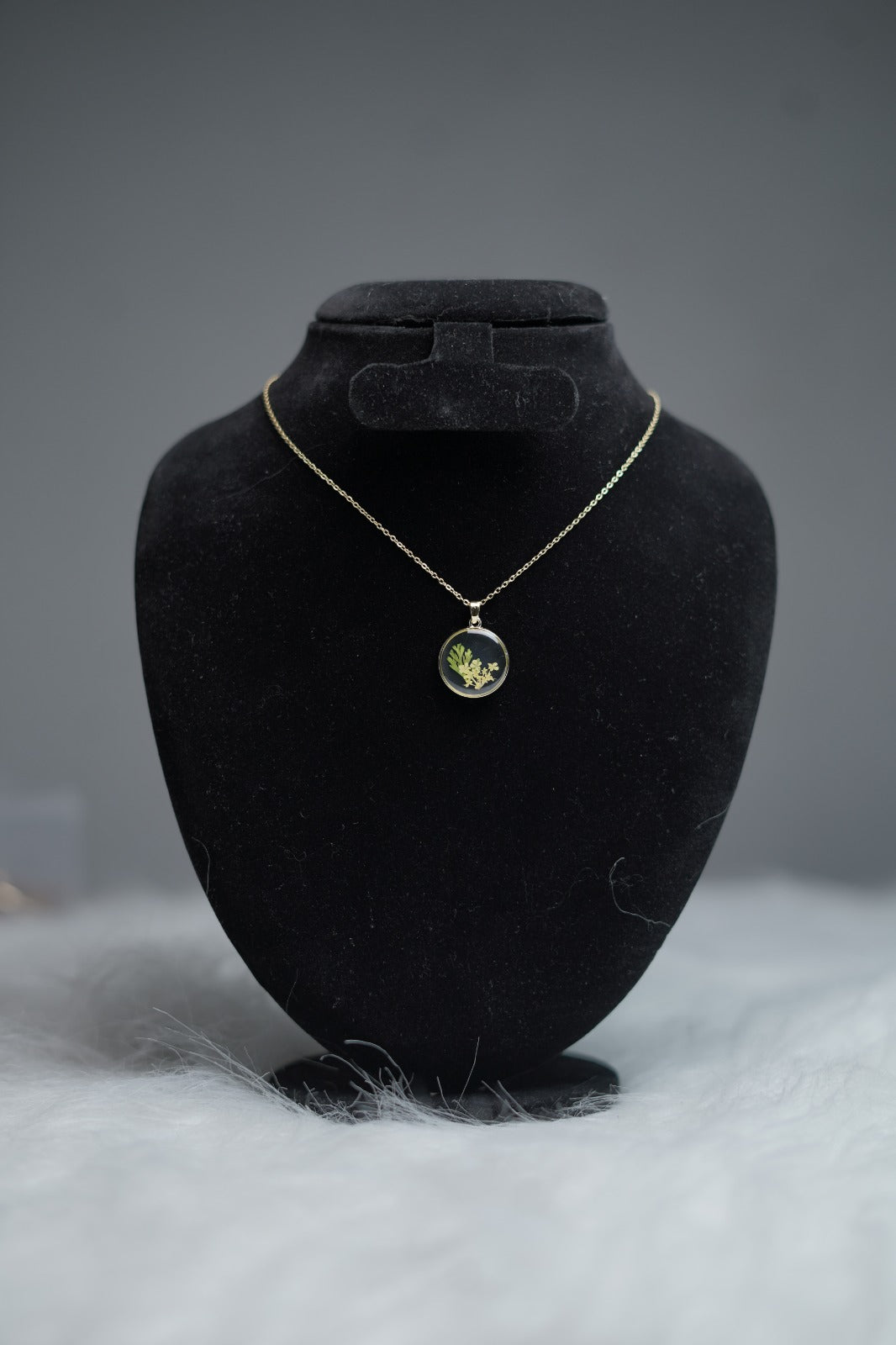 Nature-inspired necklace with resin floral insert placed on display.