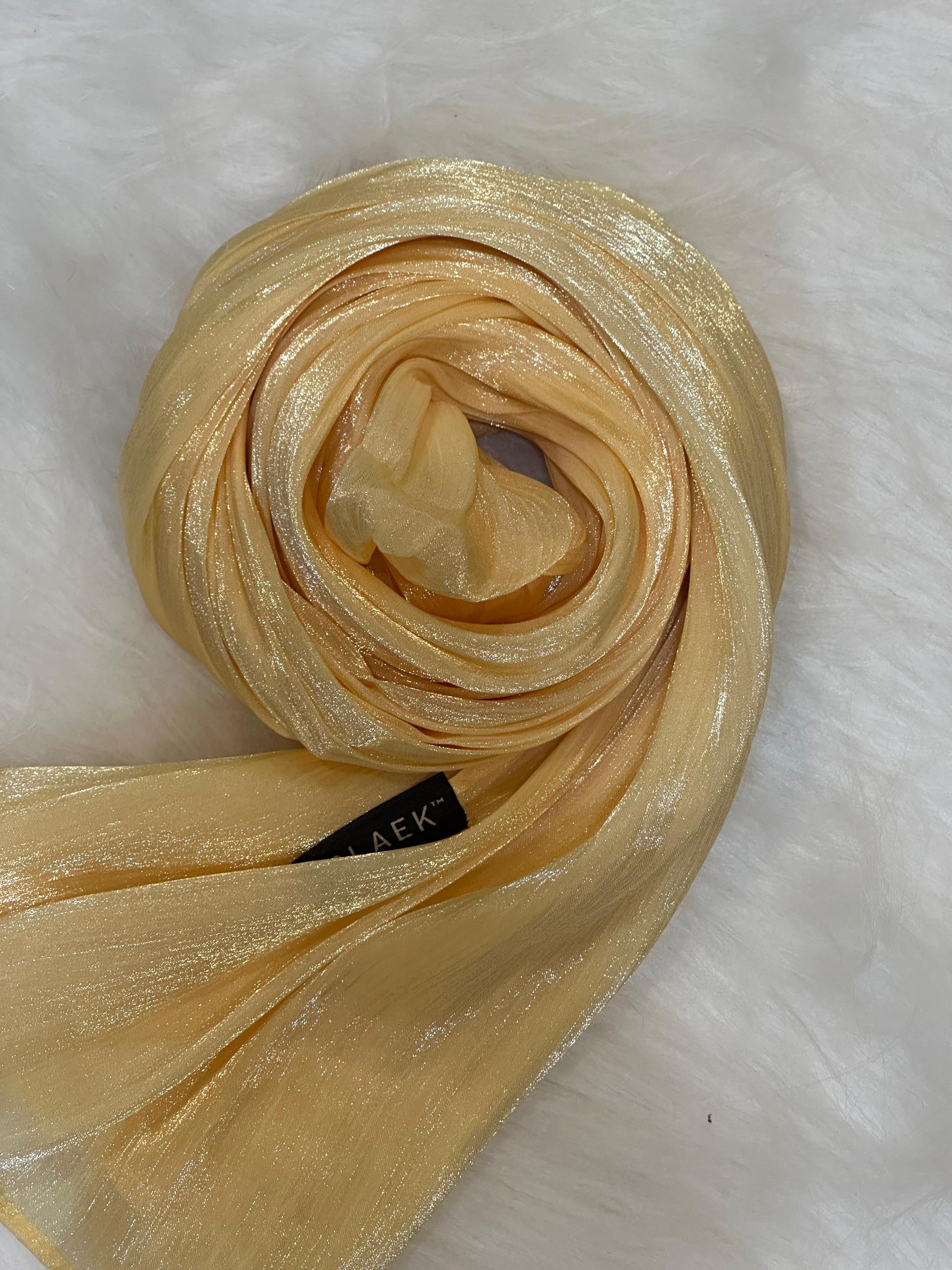 Brass yellow shimmer hijab coiled into a soft round shape with subtle shine.