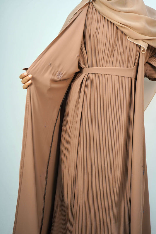 The Korean Alqa Nidha Abaya in brown, hanging open to reveal the pleated inner layer and beaded details.
