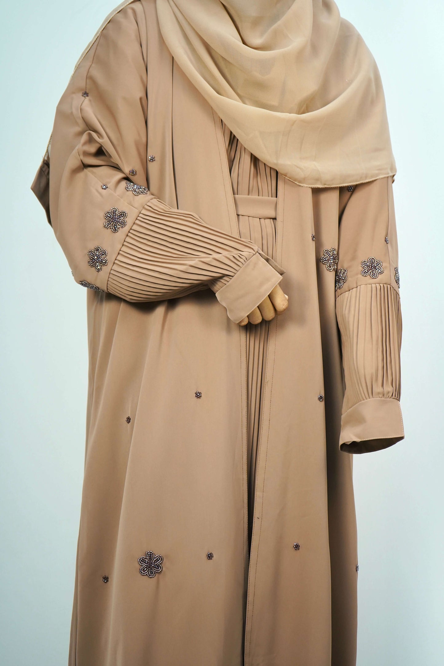 A close-up of the pleated sleeve and beaded floral design on the brown abaya.