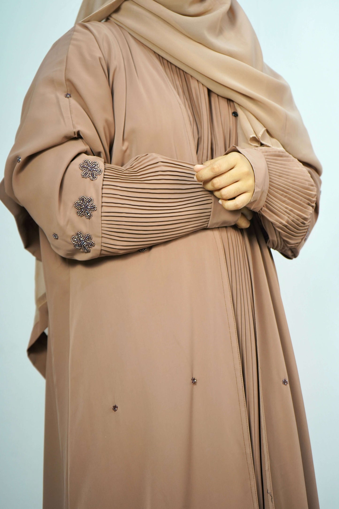 A side view of a model wearing the Korean Alqa Nidha Abaya in brown, showing the flow of the fabric, and beaded sleeve details.