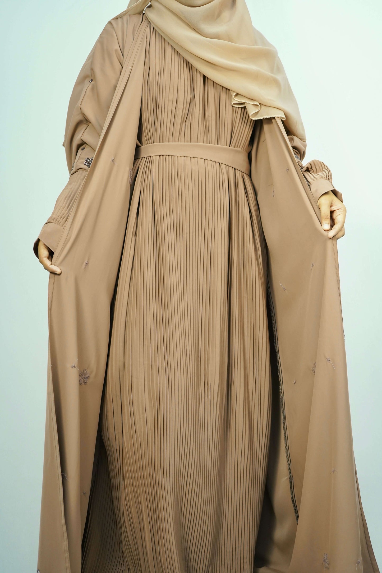 A model wearing the open-front Korean Alqa Nidha Abaya in brown, showcasing the pleated inner layer and elegant drape.