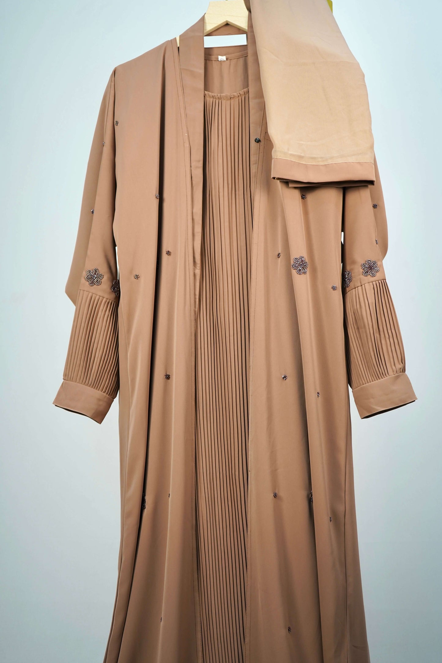 A full shot of the brown abaya, hanging to showcase the open-front design with it's matching scarf.