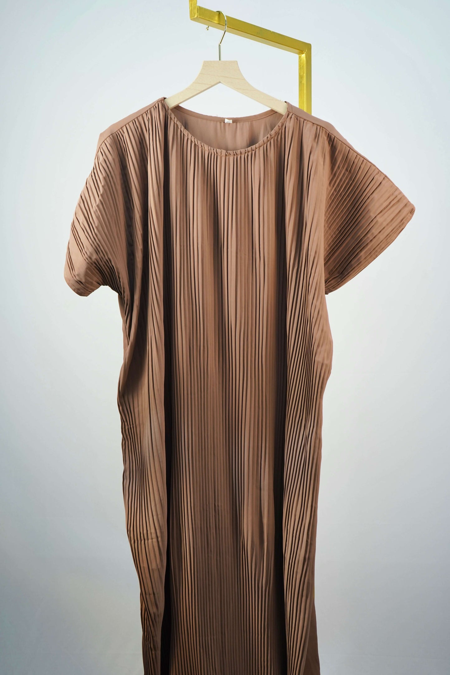 The pleated inner dress of the Korean Alqa Nidha Abaya in brown, hanging to show its full design.
