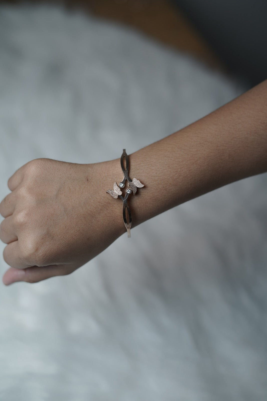 Gold Butterfly Bloom Bangle styled on wrist with elegant loop and butterfly detail.