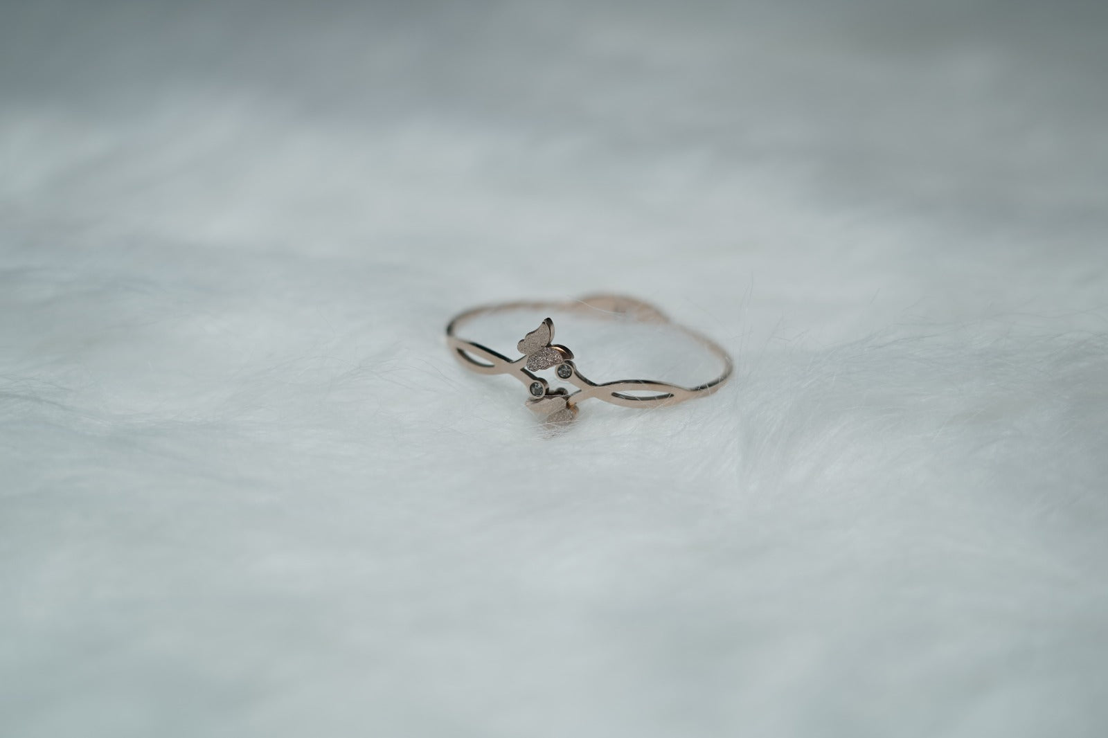 Glossy gold bracelet with dual butterfly motifs and central crystal shown on plain white surface.