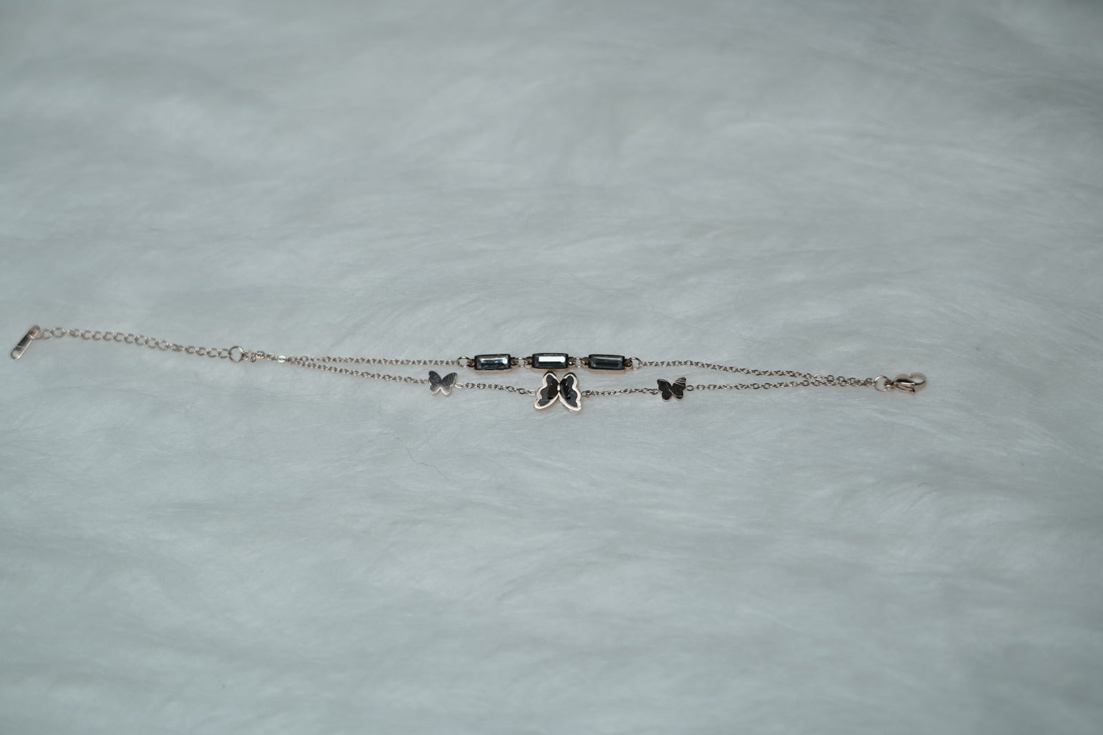 Delicate charm bracelet featuring butterflies and rectangular links on a clean white background.