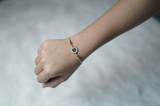 The Celestial Compass Bracelet worn on a wrist, showing the central compass charm and beaded sides.