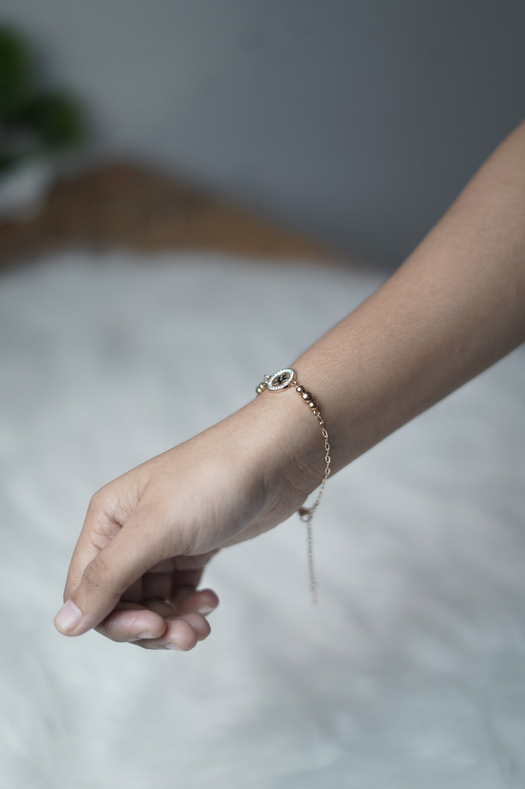 Dainty rose gold bracelet styled on hand, with a celestial-themed charm at the center.