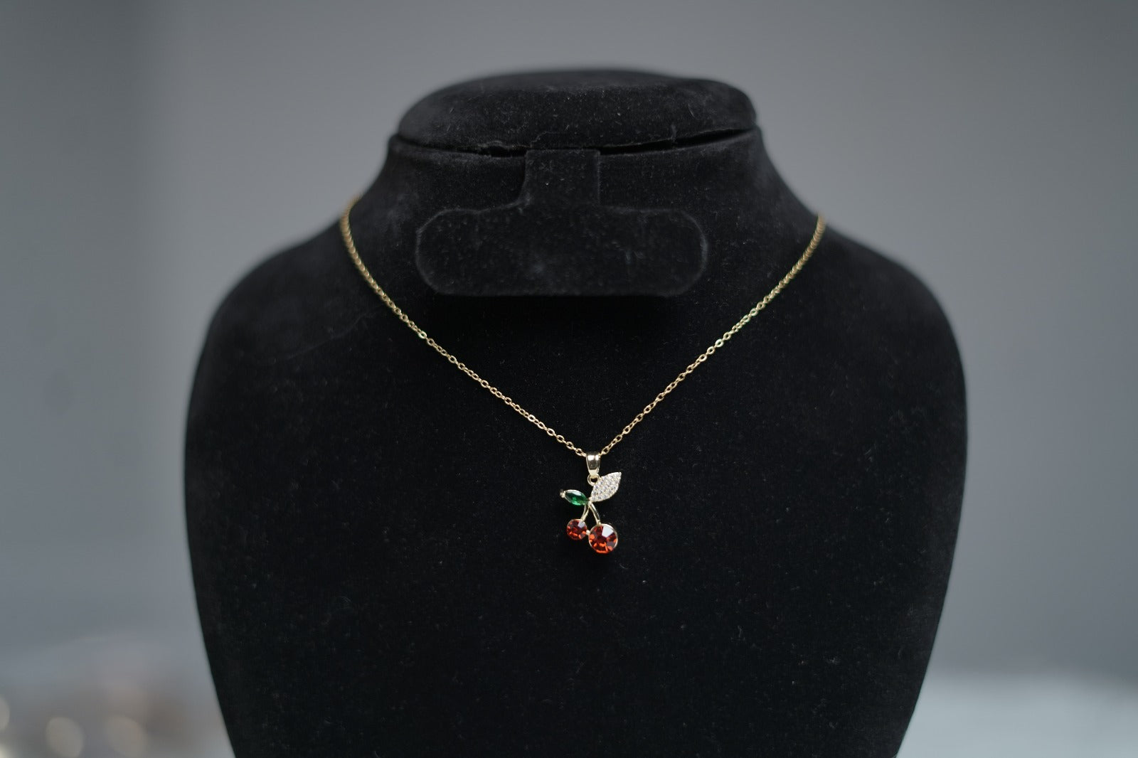 Gold chain Cherry Bloom Necklace displayed on neutral stand background.