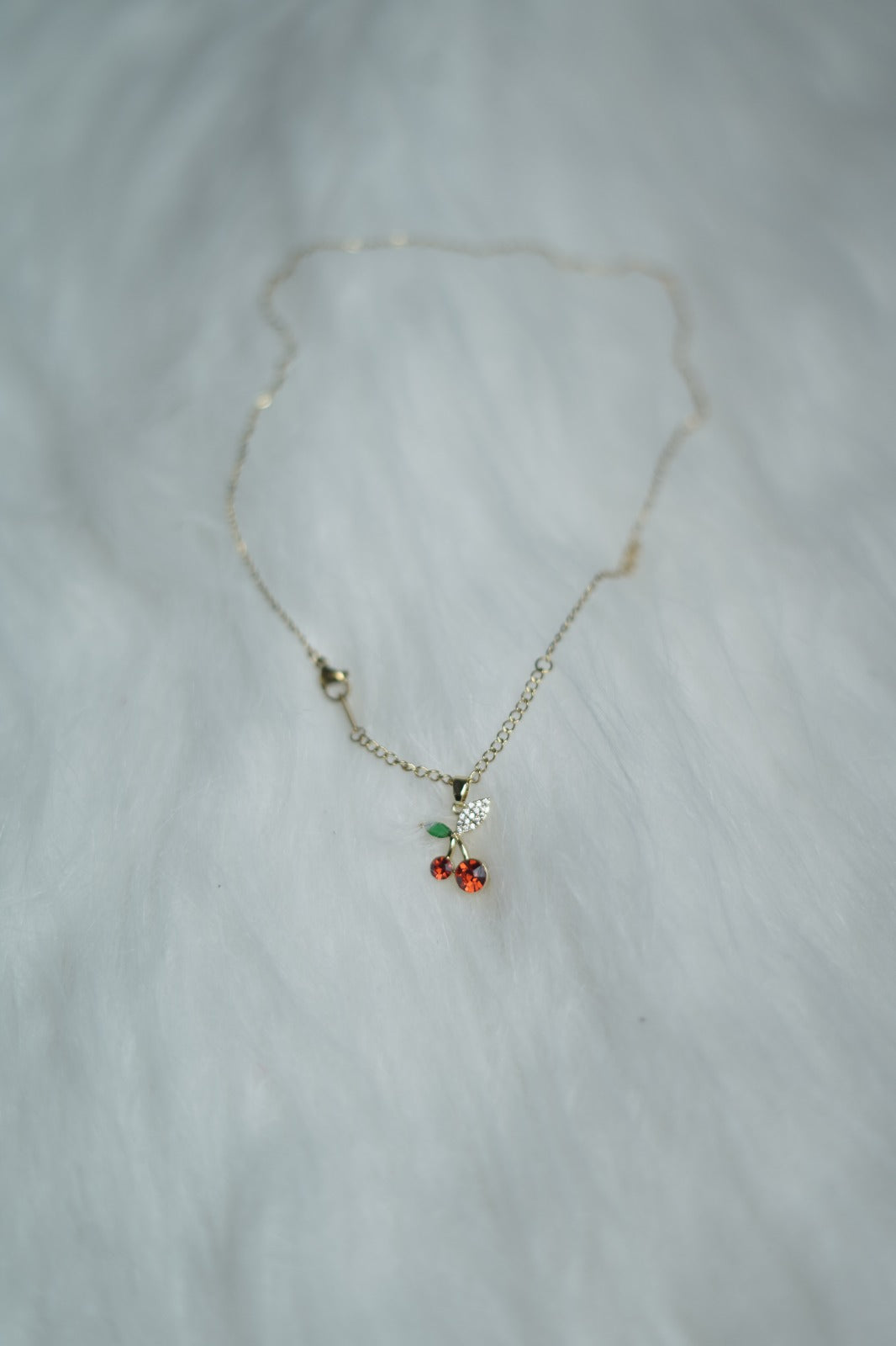Close-up of Cherry Bloom pendant with red and green stones.