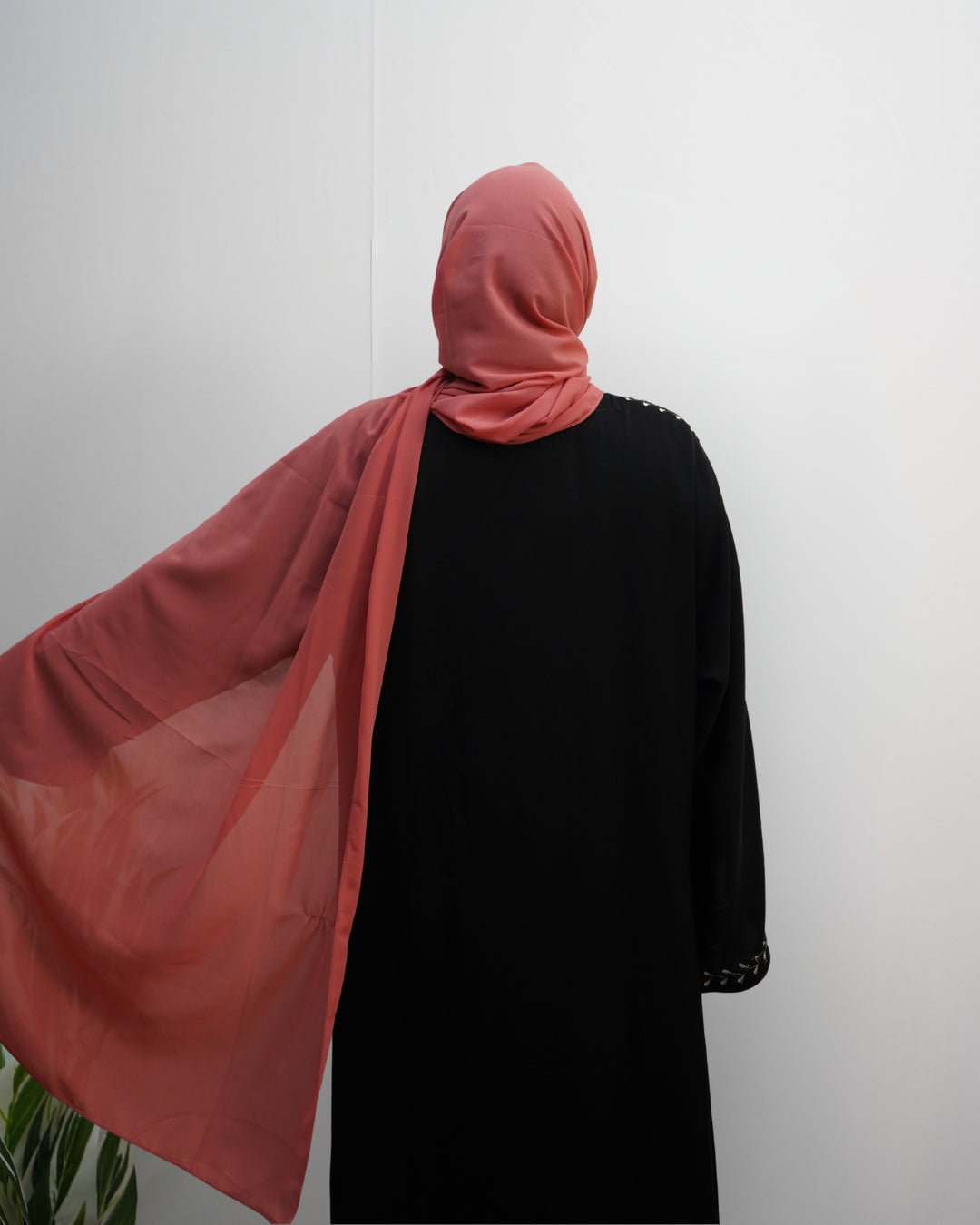 Coral pink chiffon hijab draped elegantly over the shoulder, showing lightweight flow.