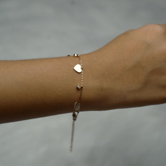 Rose gold bracelet with heart and crystal charms on wrist