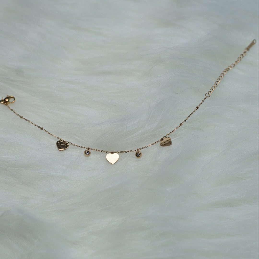 Rose gold bracelet with heart and crystal charms on wrist