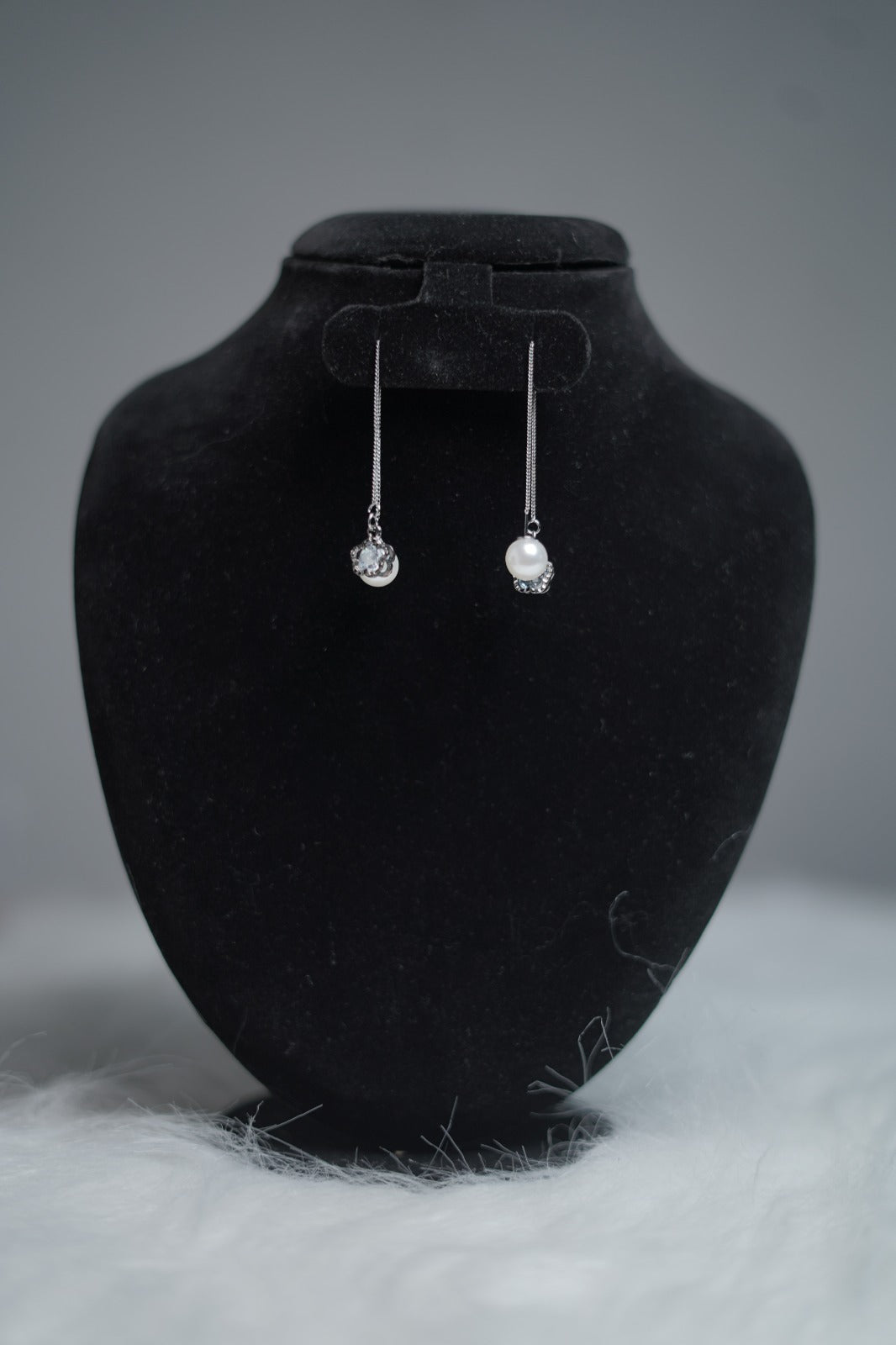 Dual Charm Pearl & Crystal Earrings hanging on display stand.