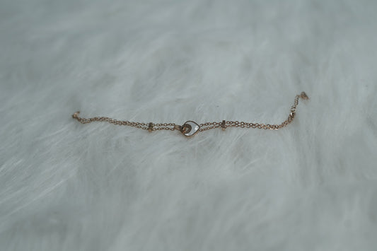 Bracelet showcasing a central orbit heart pendant and delicate double chains on a soft background.