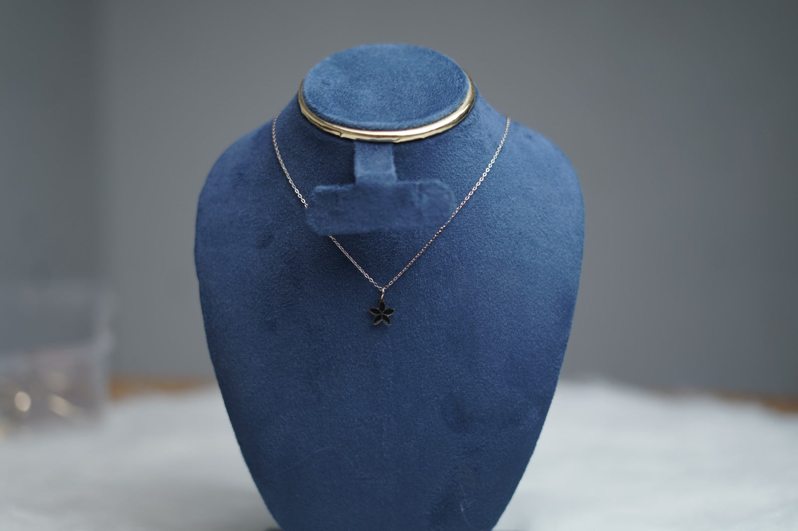 Jewelry stand showcasing glossy black side of bloom petal necklace.