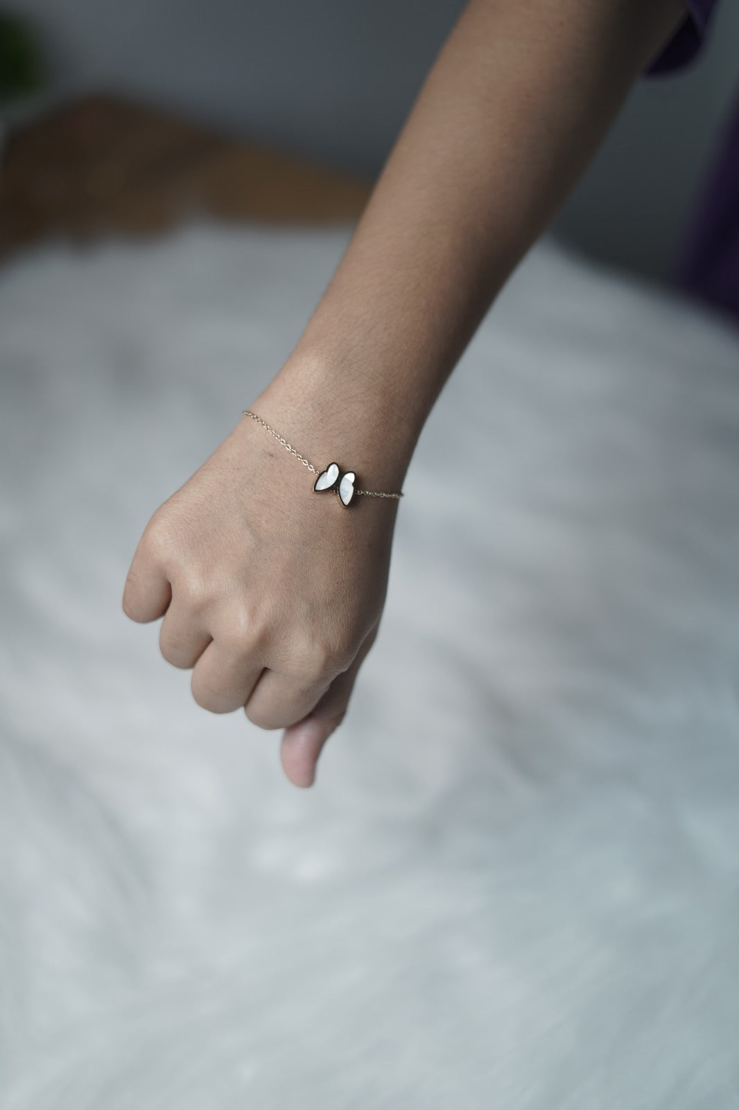 Minimal butterfly bracelet highlighting the white side charm in natural light.