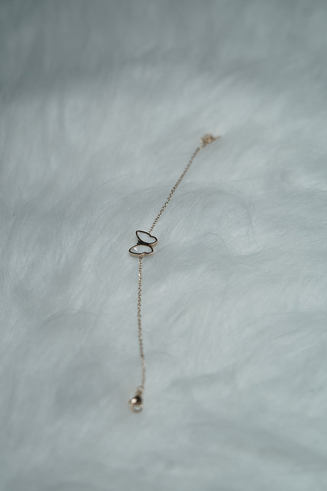 Bracelet styled on hand with the white butterfly side outward, showing a delicate look.