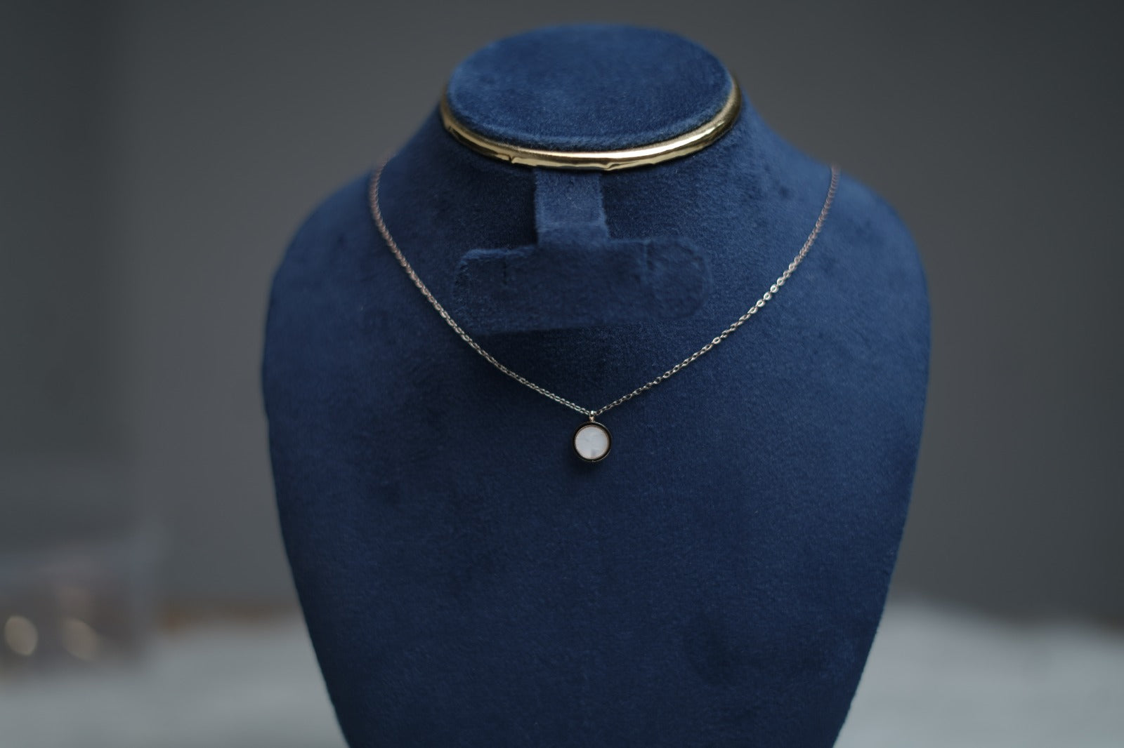Dual Sided Halo Glow Necklace showcasing white pearl side on jewelry stand.