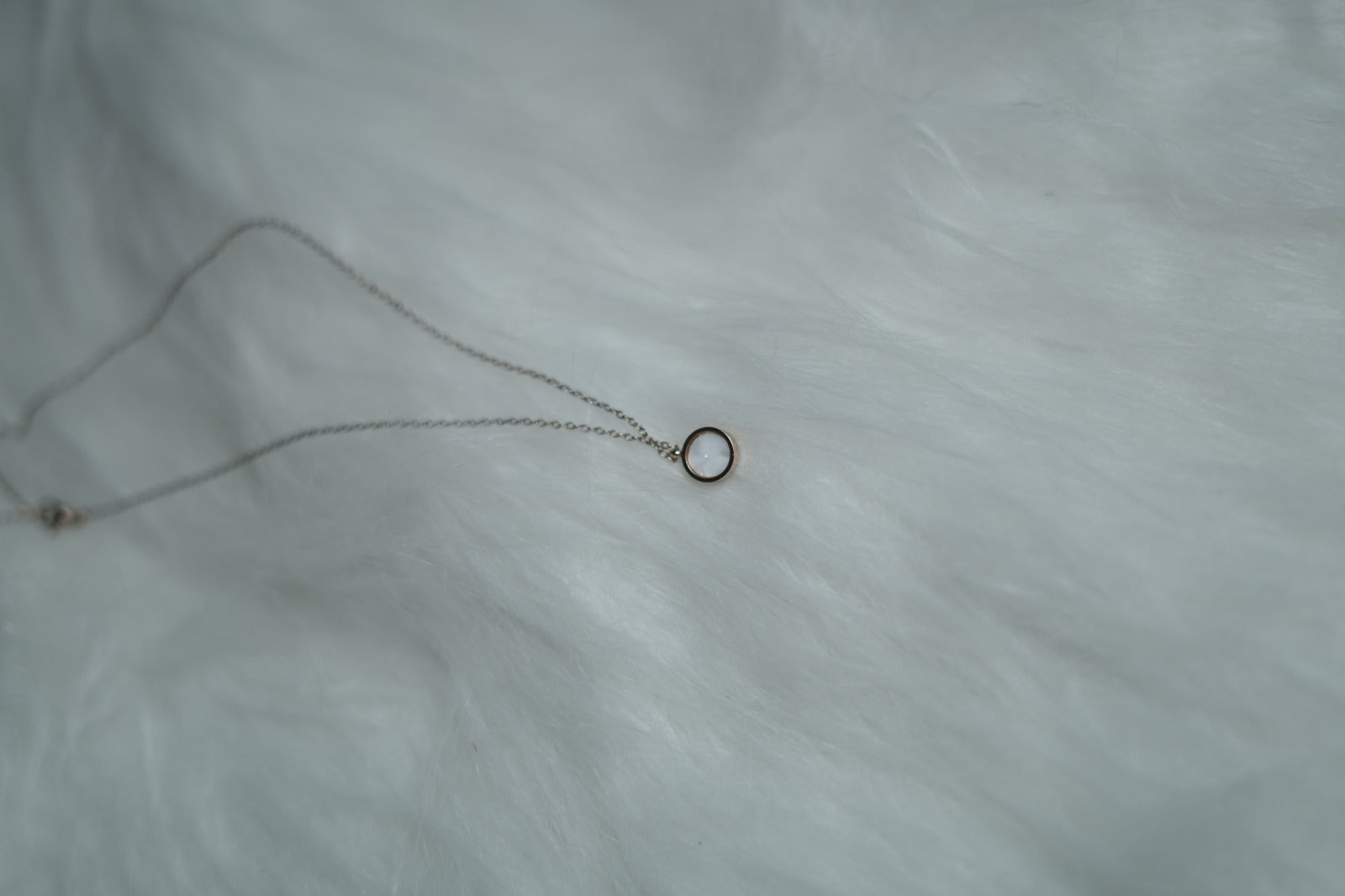 Reversible pendant with luminous white shell finish on clean background.