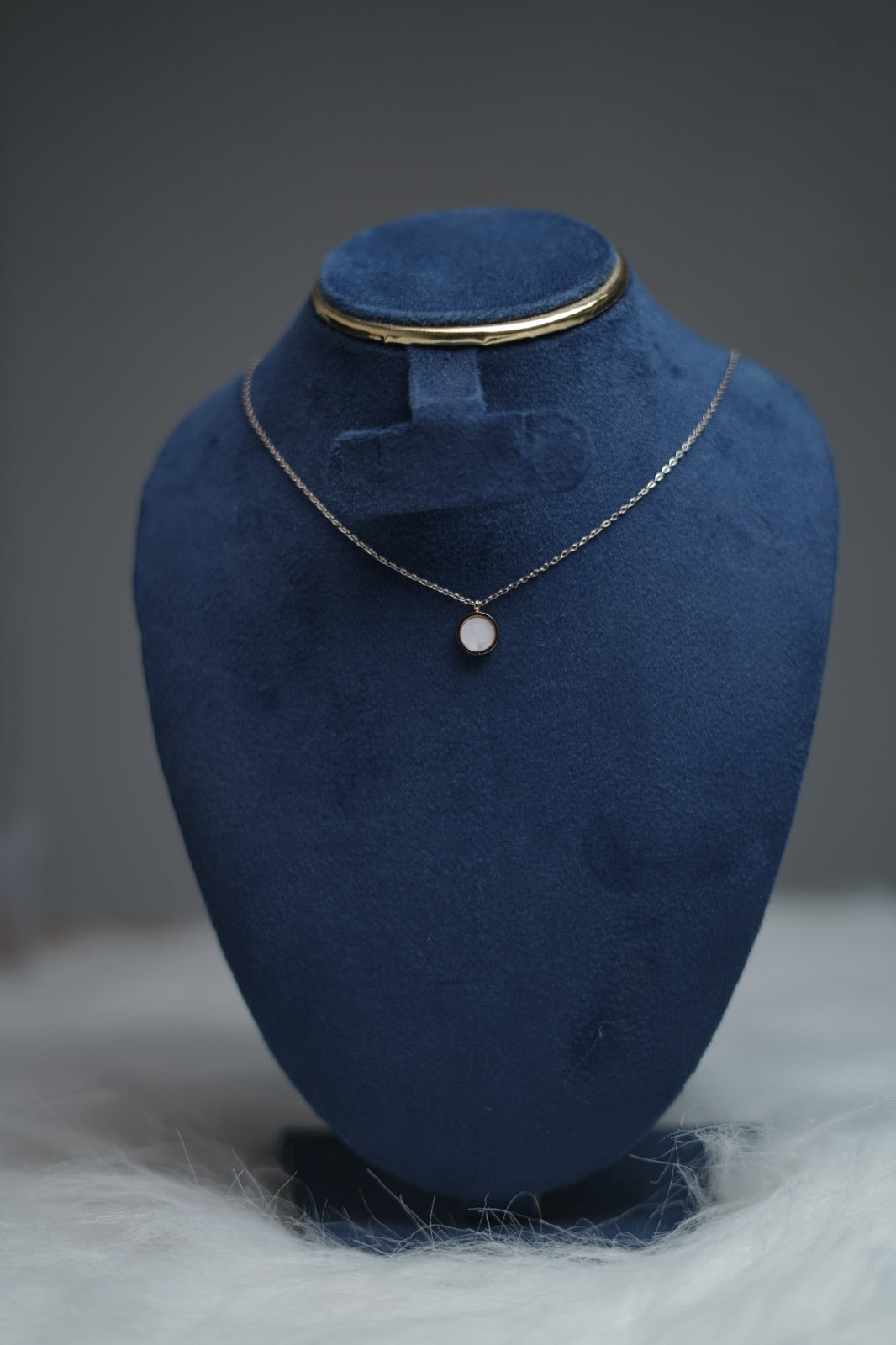 Luminous white inlay pendant placed on necklace holder for presentation.