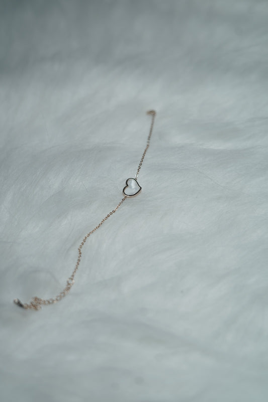 Dual Sided Heart Bracelet (Black & White) laid flat with the white heart side facing up on a soft white surface.