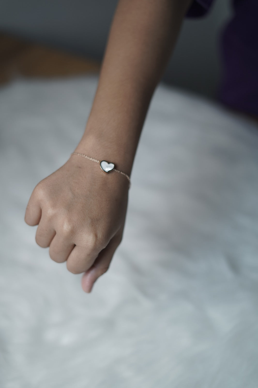 Bracelet resting gently on the hand with the white heart side styled outward.