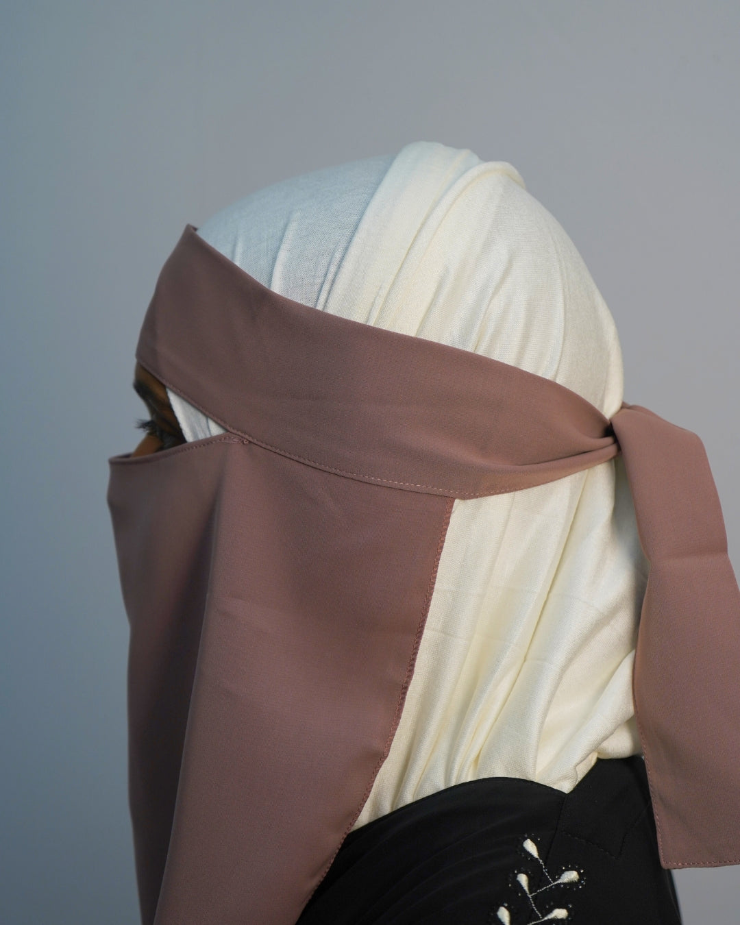 Side profile of dusty brown chiffon one layer niqab with adjustable tie-back straps.
