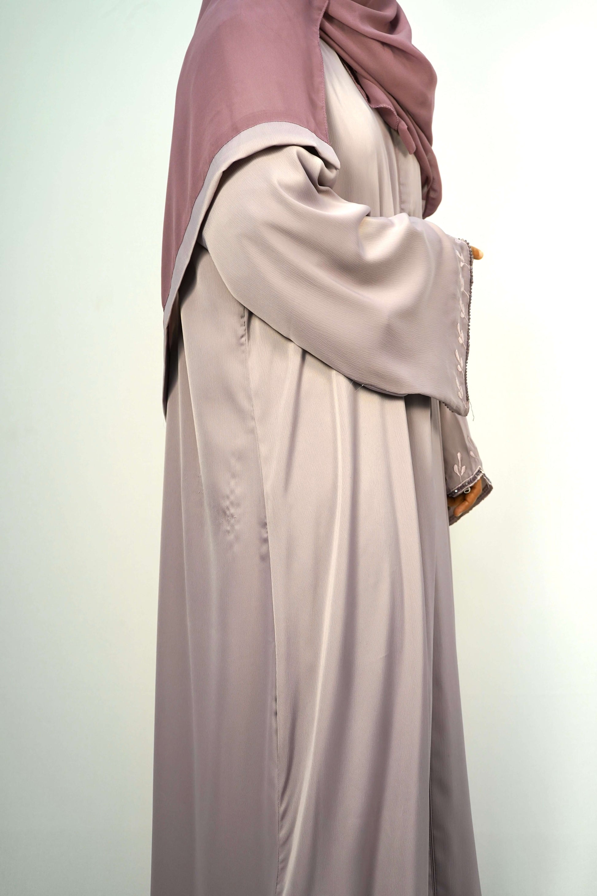 The elegant movement and drape of the dusty purple abaya from a side perspective.