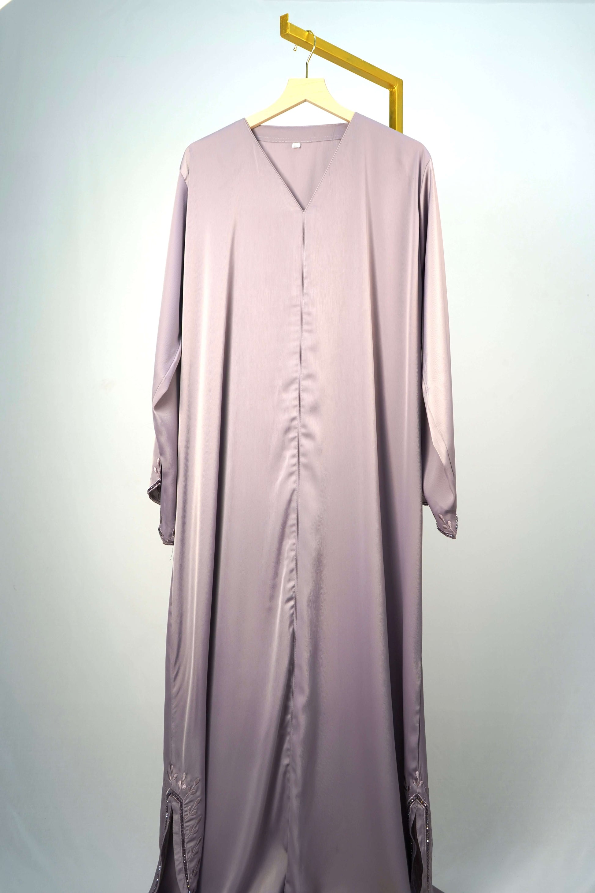 A full shot of the Tiktok Indonesian Abaya in dusty purple, hanging to showcase its full design and silky fabric.