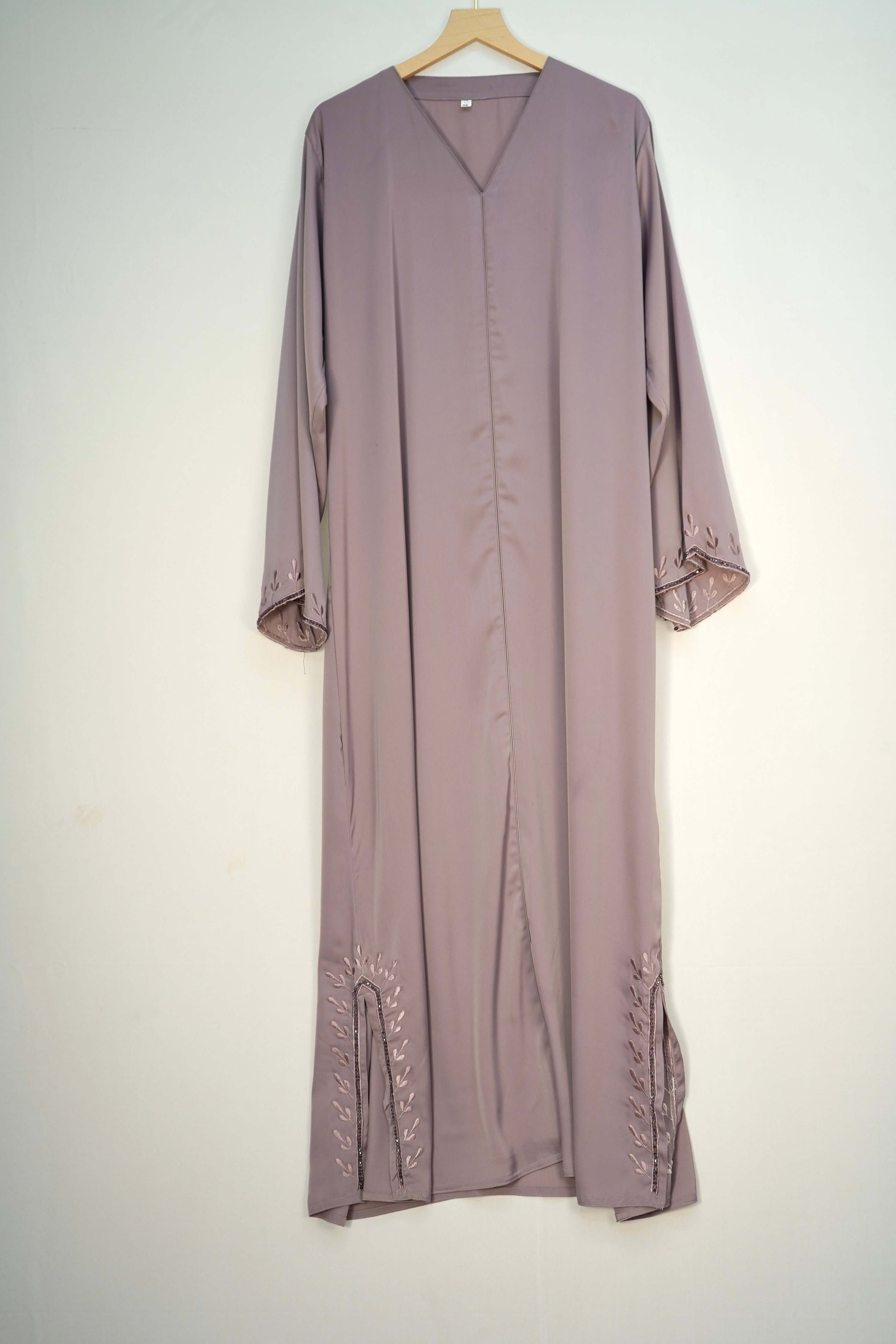 The graceful drape of the Tiktok Indonesian Abaya in dusty purple, hanging to reveal the V-neck and embroidered hem.