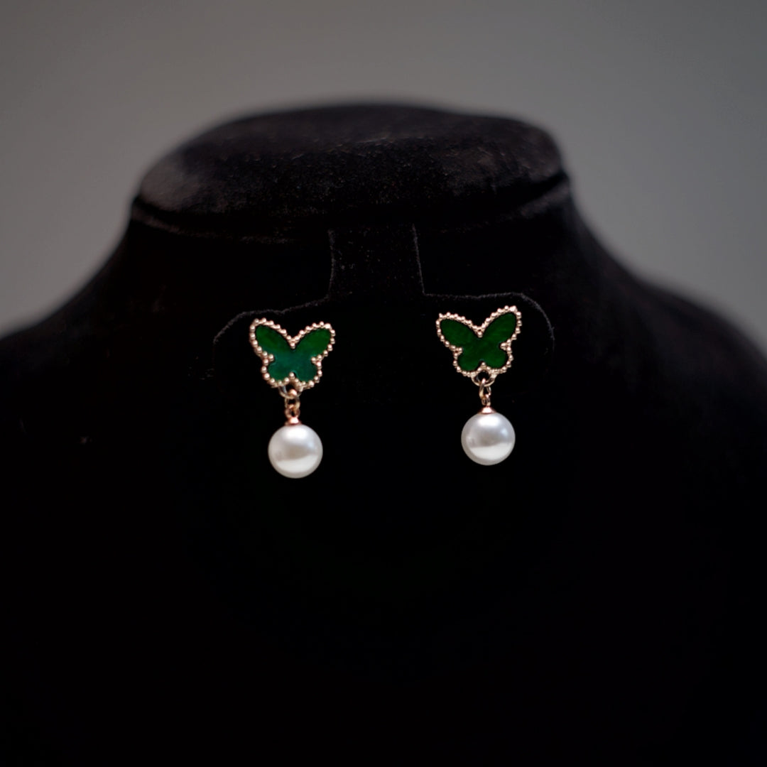 Close-up view of butterfly-shaped studs with pearl drops, highlighting the delicate rose gold beaded edges.