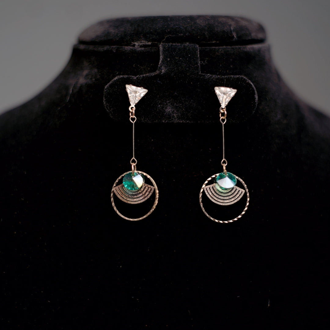 Long rose gold earrings with modern shapes, including triangle tops, green crystals, and layered metallic accents.