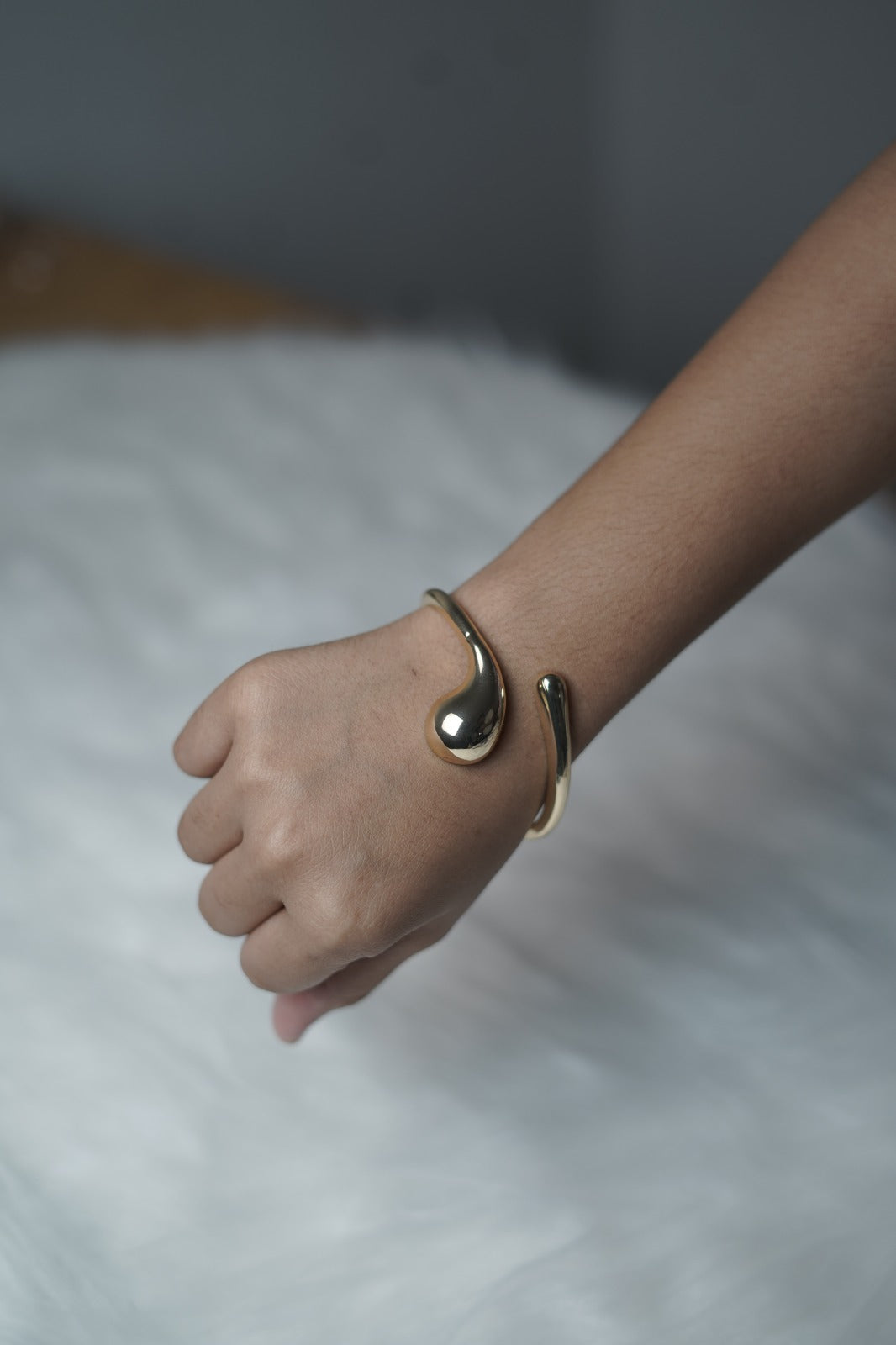 Fluid Form Bangle worn on wrist showcasing curved gold silhouette.