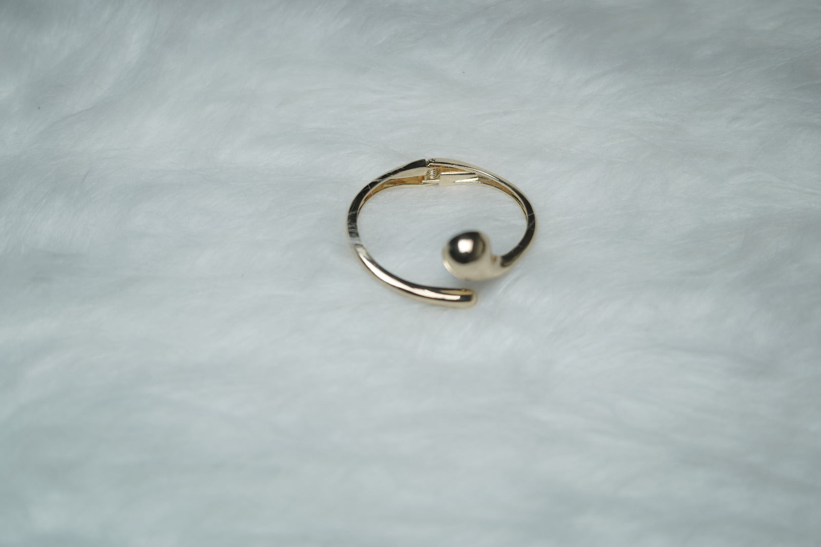 Glossy fluid form bangle photographed flat on white background.