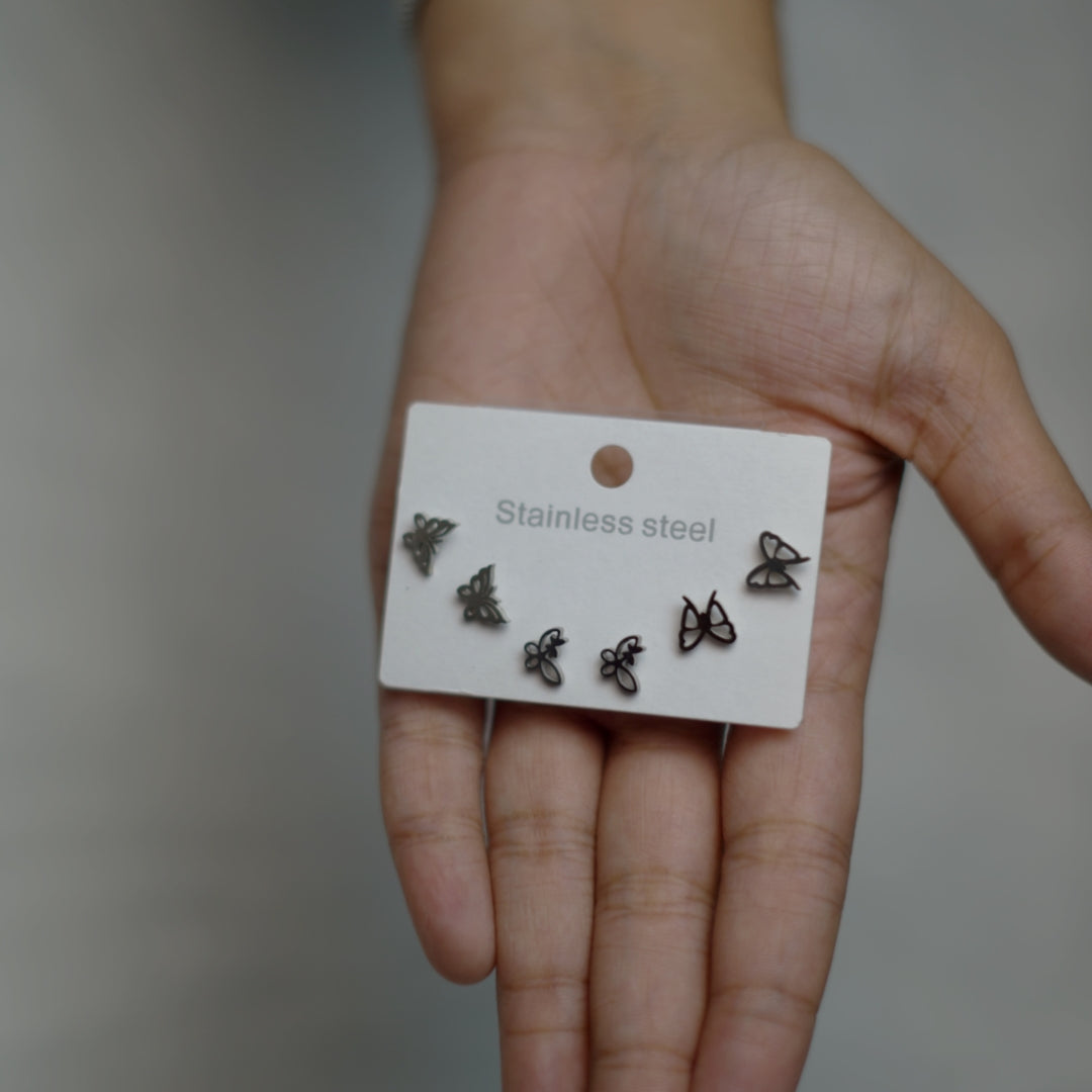 Silver butterfly earrings in assorted styles, crafted with polished alloy and displayed on an open hand.