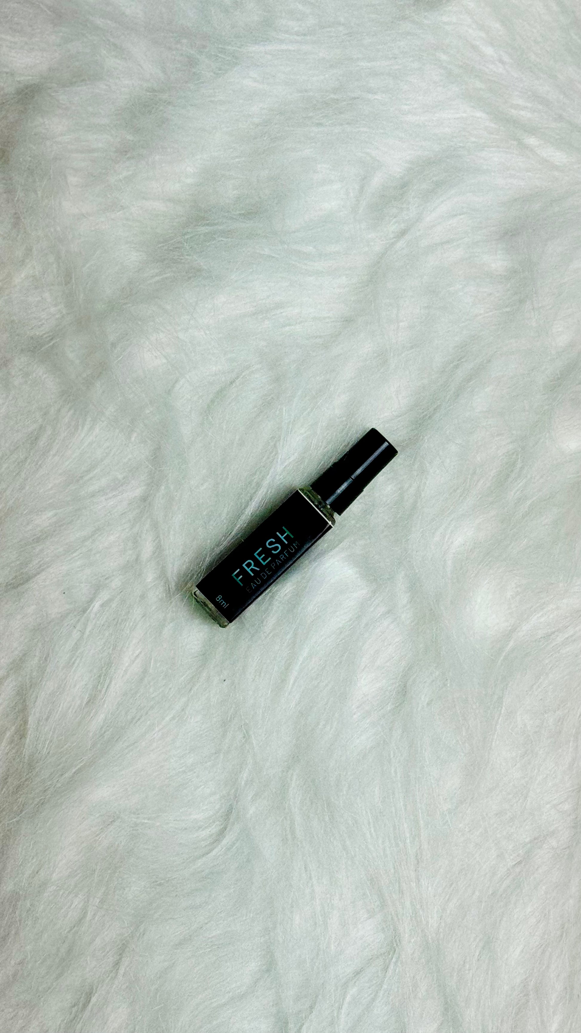 Fresh Perfume 8ml resting sideways on a smooth white surface.