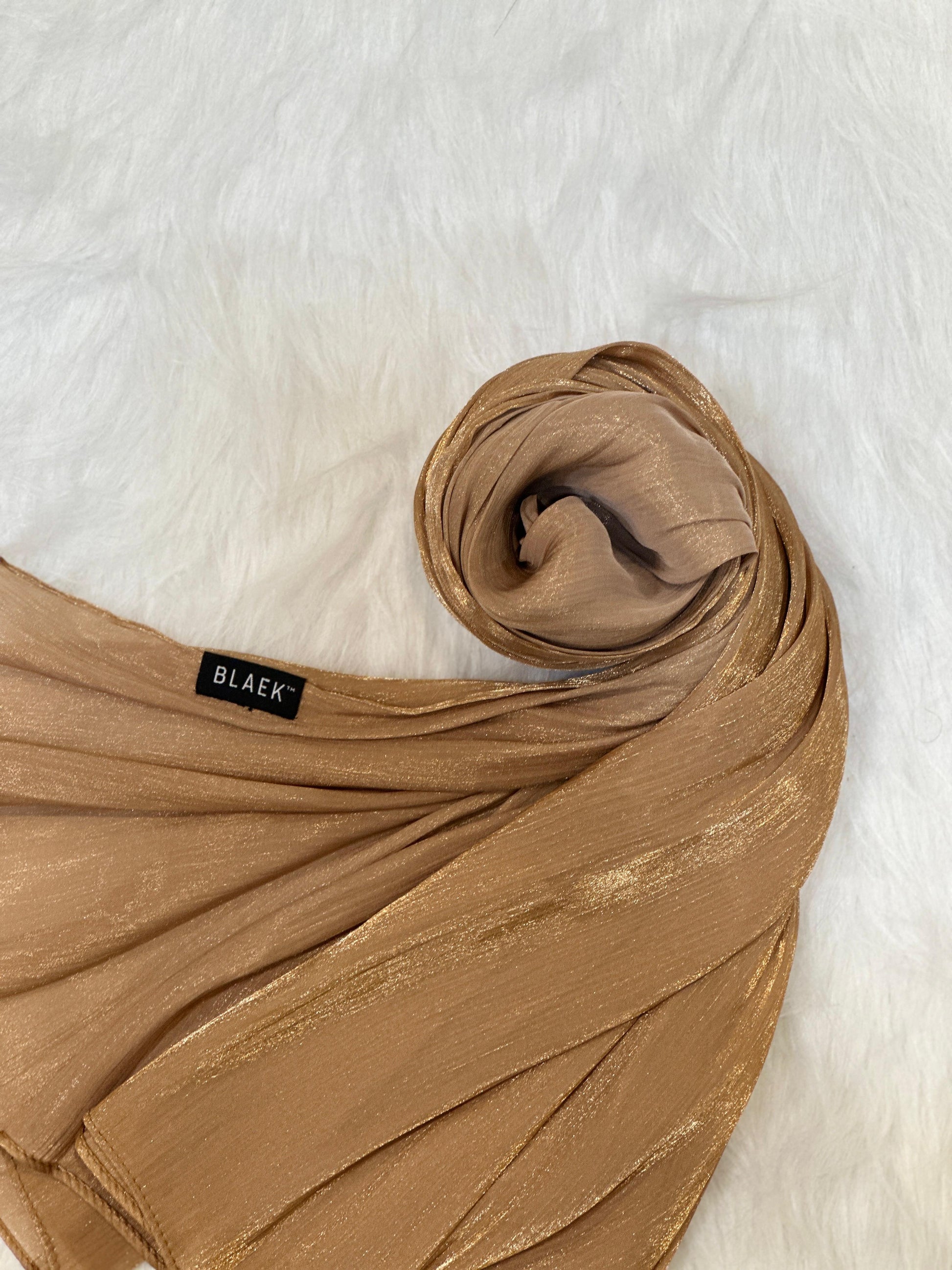 Golden-toned shimmer hijab in a round wrap layout, styled for visual appeal.
