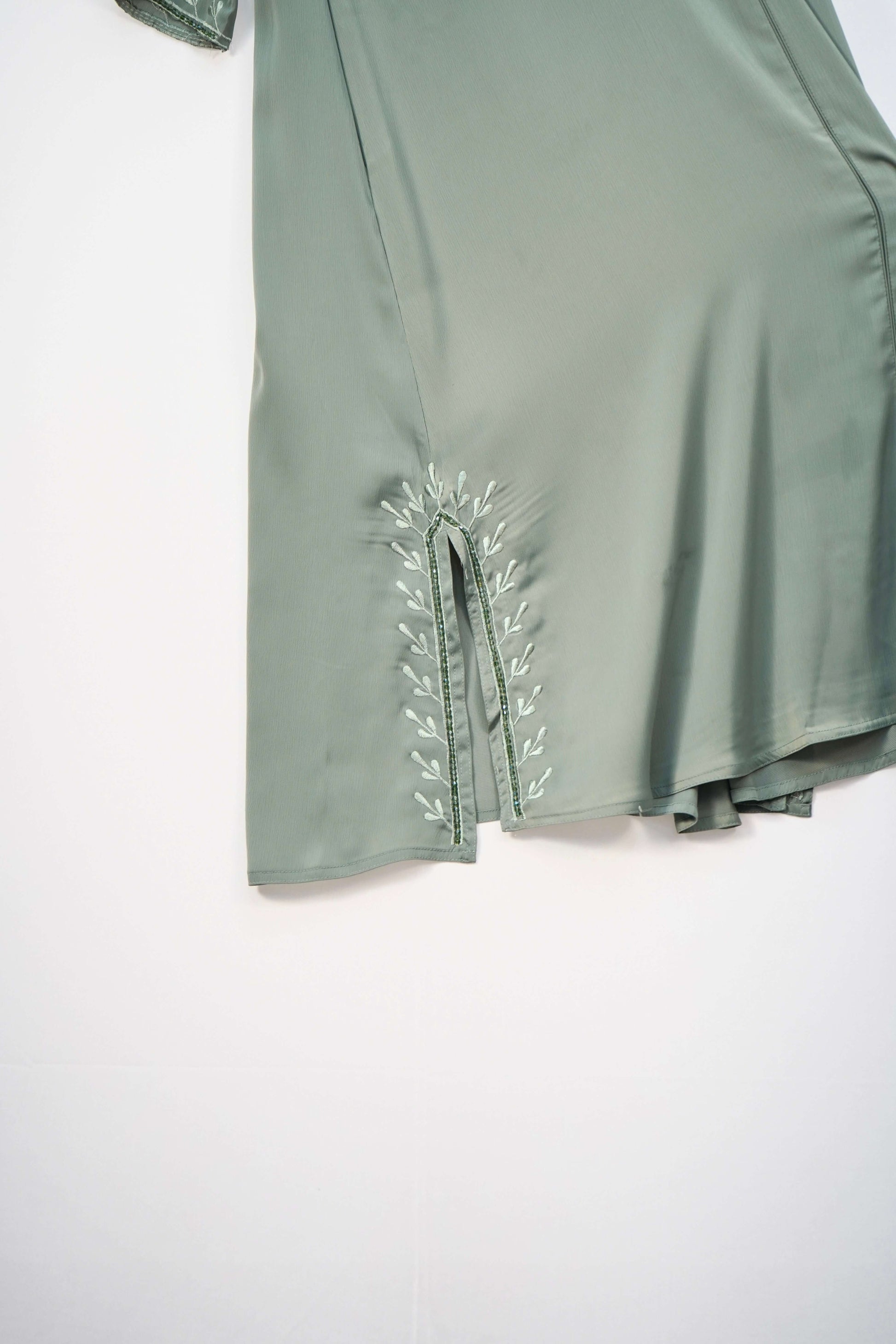 A detailed view of the silky texture of the green abaya fabric.