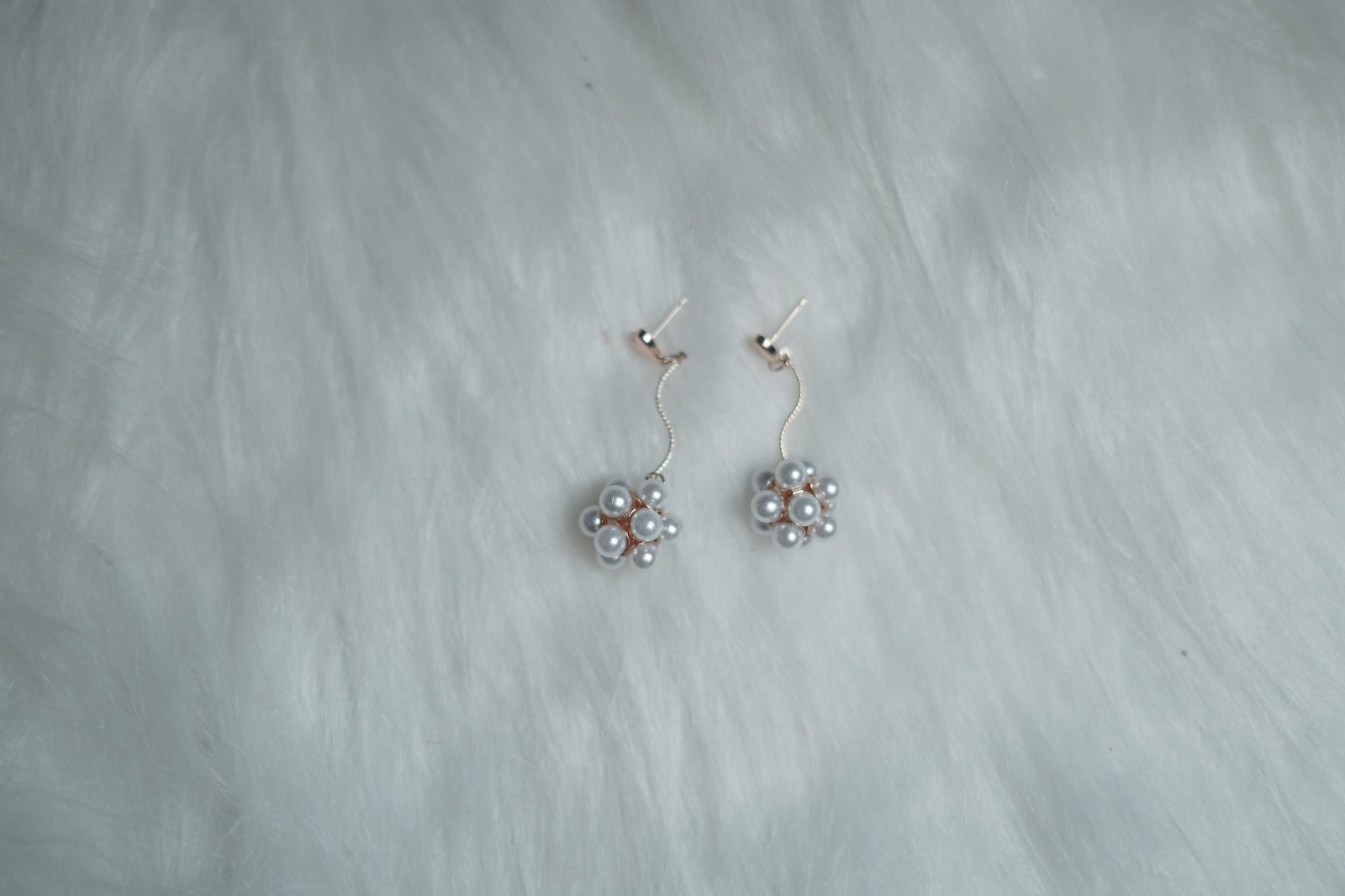 Heart-shaped stud earrings with pearl drop design arranged neatly on a soft white surface.