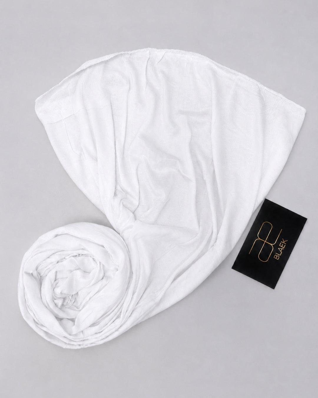 White kids jersey hijab laid flat with one end softly rolled to highlight the fabric drape